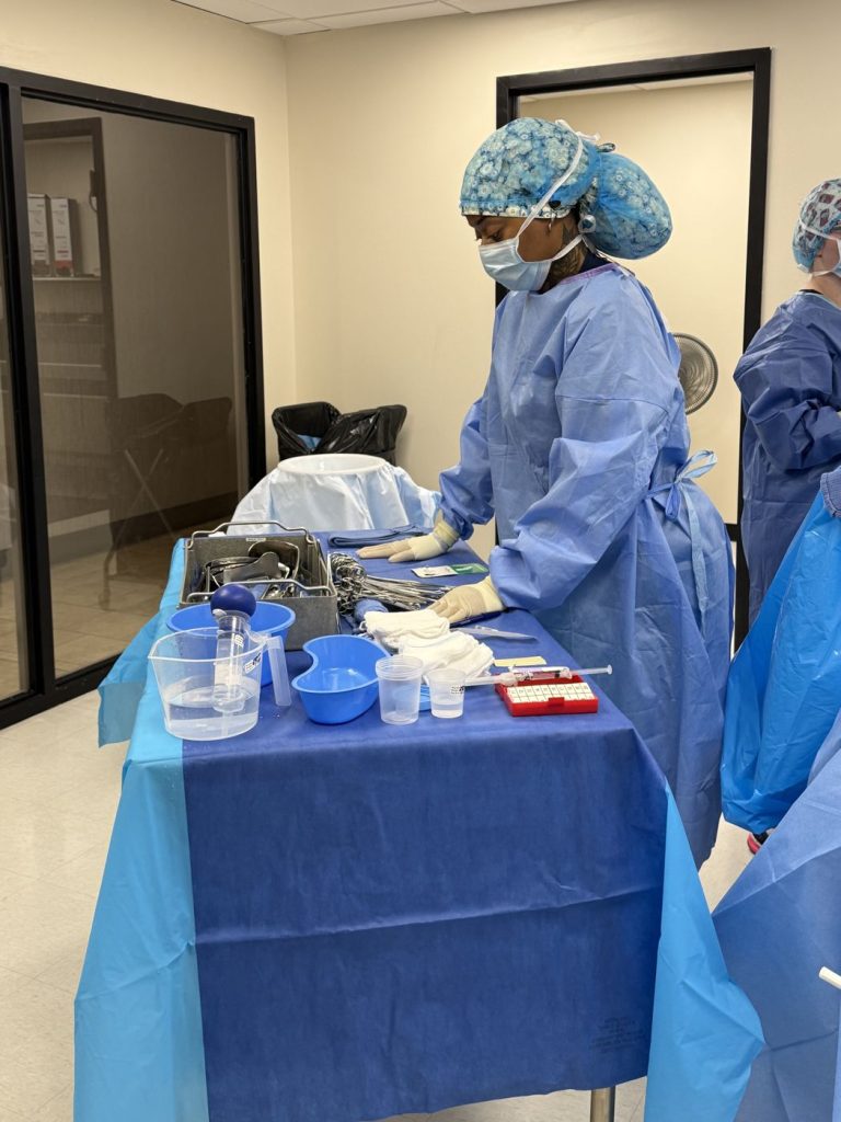 Surgical tech student setting up instruments on the back table in the surgical operatory lab