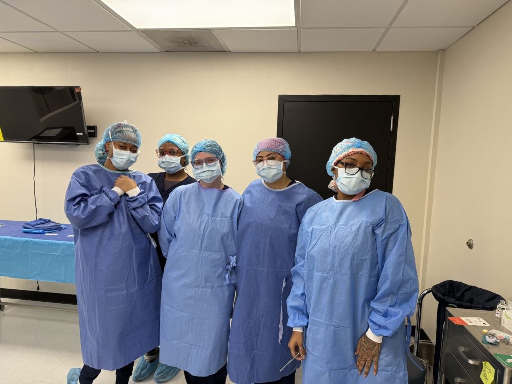 Group of Midwest Institute surgical technology students in surgical gowns and caps